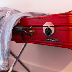 Rambler: Red leather suitcase with jean jacket hanging on it