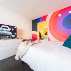 Rambler: view of one queen bed with RAD wall graphic and TV in view