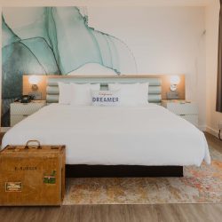 Bed in Rambler suite with Dreamer pillow and blue water color graphic behind the headboard