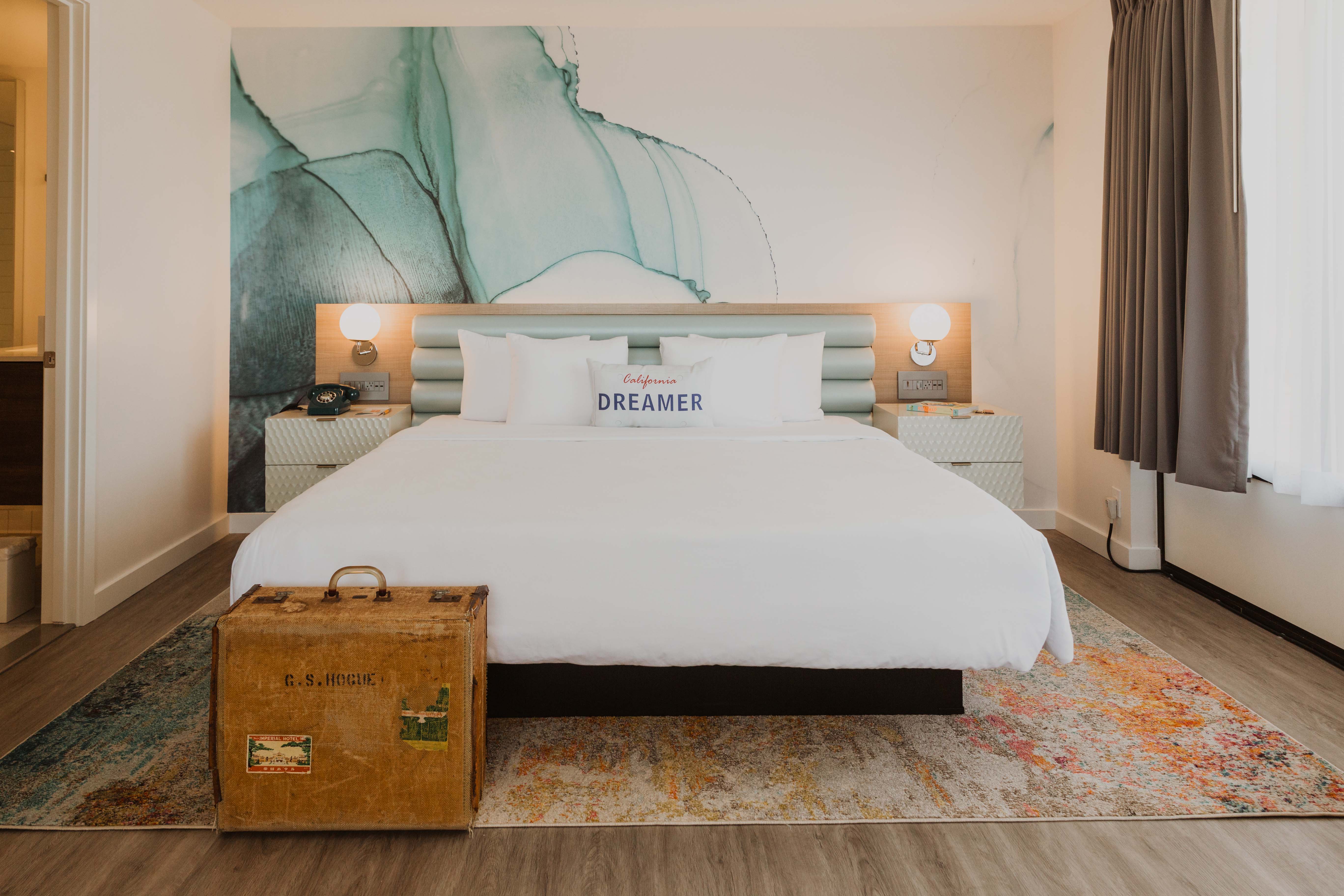Bed in Rambler suite with Dreamer pillow and blue water color graphic behind the headboard