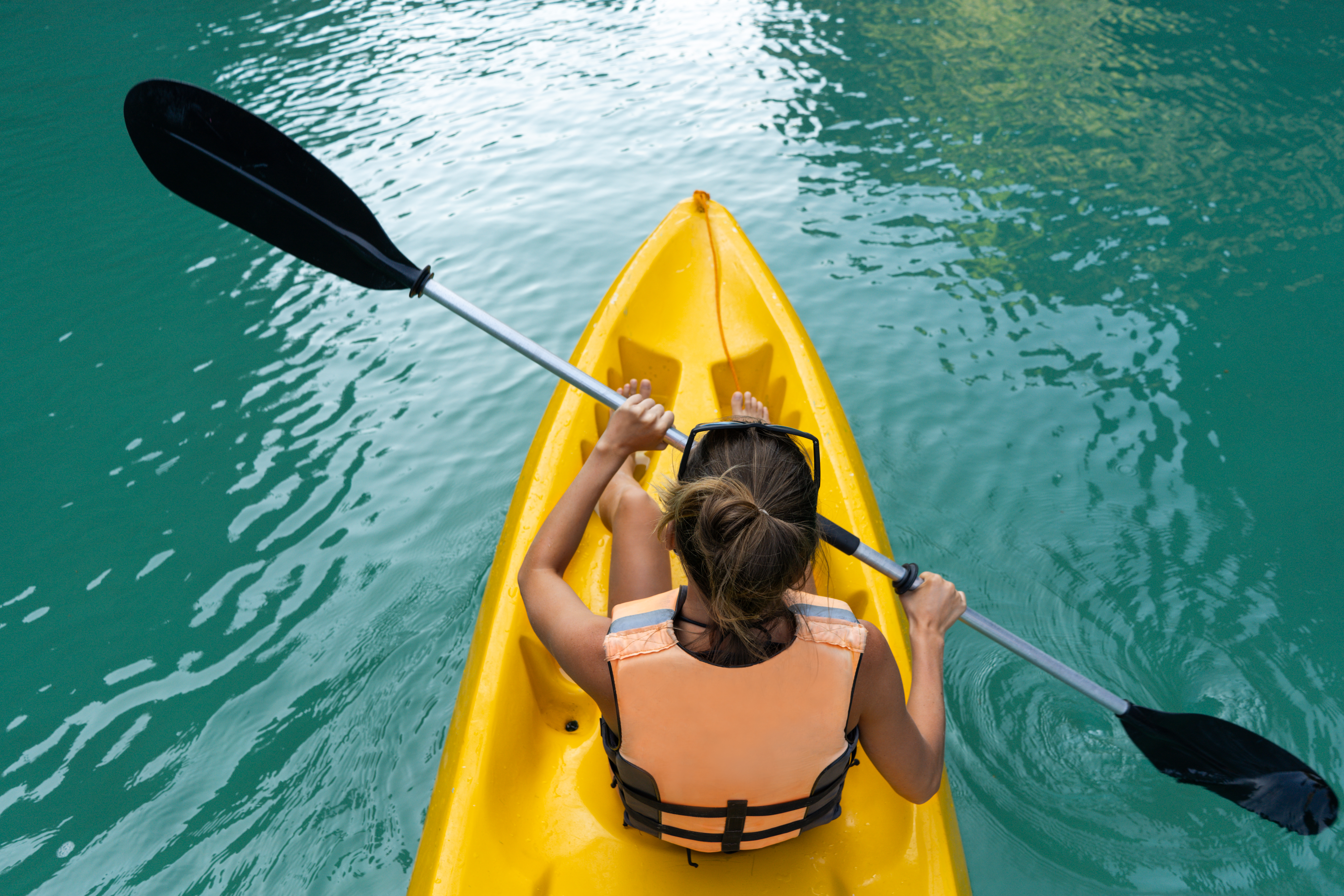 View from above of woman in kayak in blue water
