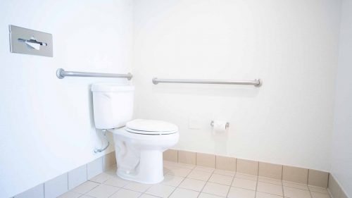 Toliet in ADA bathroom with hand rails next to it