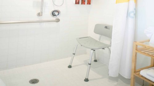 Chair and wall handle rails in ADA accessible walk in shower