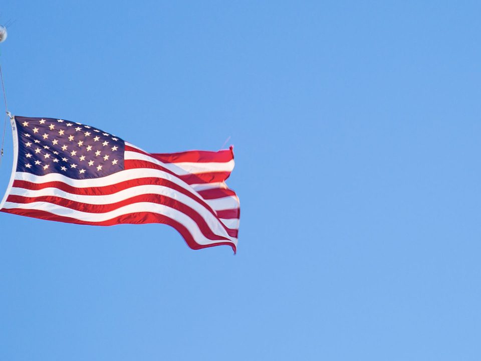 American flag blowing in the wind in a blue sky