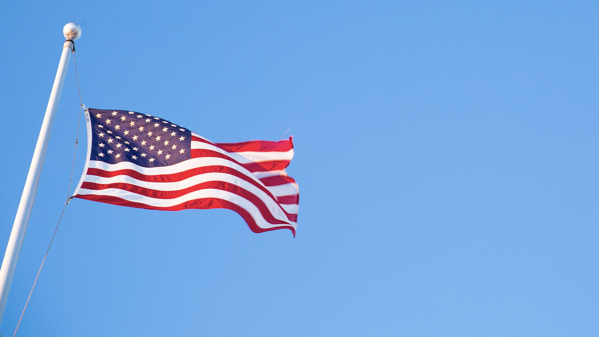 American flag blowing in the wind in a blue sky