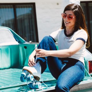 Girl tying roller skates on the back of a truck